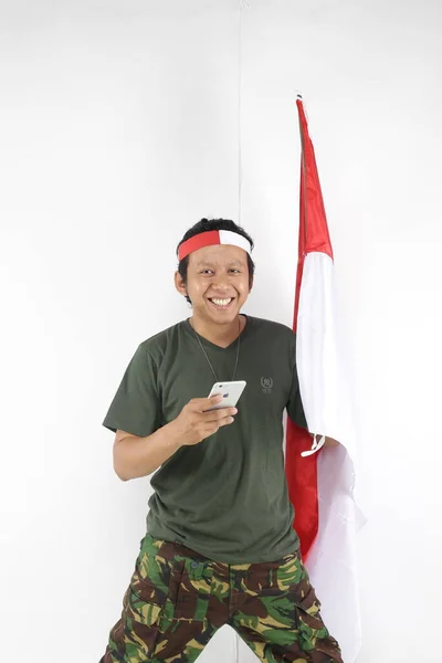 Pria Indonesia Bahagia Menggunakan Smartphone Dan Memegang Bendera Putih Merah — Stok Foto