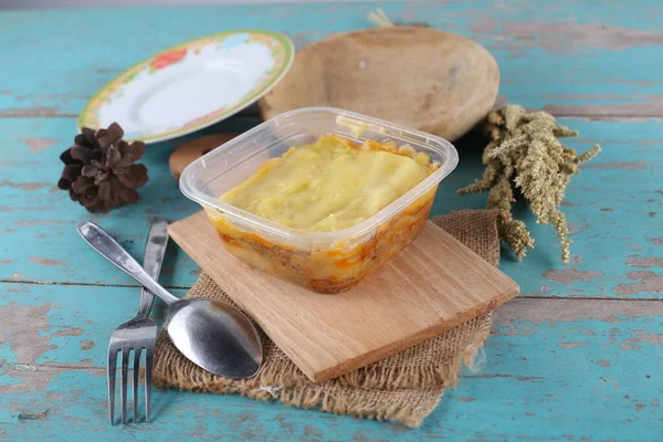 Closeup of plastic container with home-cooked vegetables on blue wooden table