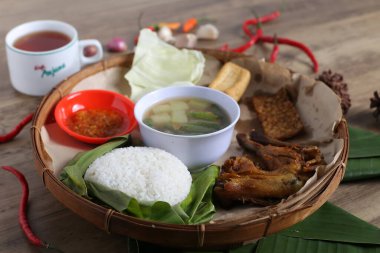 Tahta tabak, kızarmış et, sebze aperatifler, bir kase sos, ahşap masa arkaplanı.