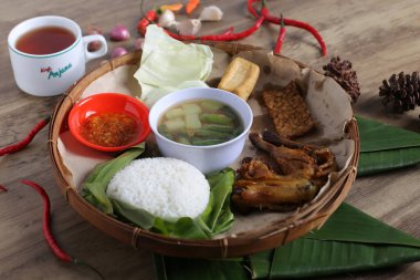 Tahta tabak, kızarmış et, sebze aperatifler, bir kase sos, ahşap masa arkaplanı.