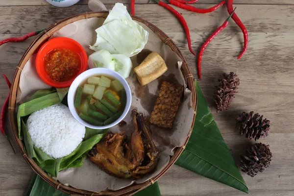 Tahta tabak, kızarmış et, sebze aperatifler, bir kase sos, ahşap masa arkaplanı.