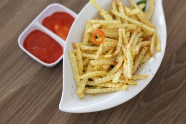 Ahşap arka planda patates kızartması tabağı. Tahta arka planda ketçaplı patates kızartması.