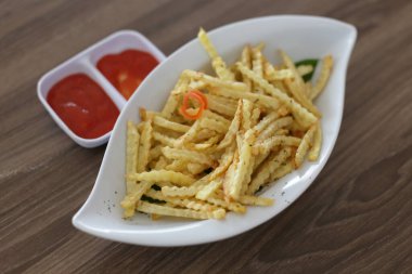 Patates kızartması ahşap masanın üstünde. Üst tabakta patates kızartması, küçük kaselerde domates sosu.