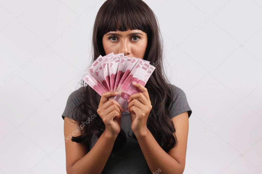 asian woman showing rupiah money. Woman holding and showing Indonesian money rupiah in hand covered face