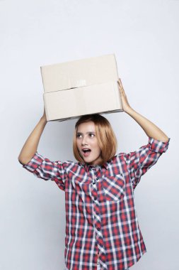 Şaşırmış yüzlü bir kadın paketi. Paket kutusunu sunan kırmızı üniformalı teslimatçı kız.