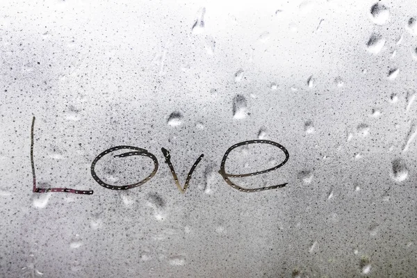 The word love on the wet window in the rain greeting card for Valentines day holiday