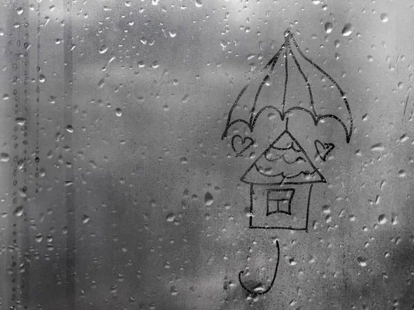drawn house under an umbrella on a wet window with copy space