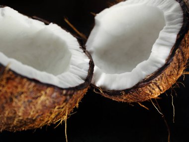 Karanlık bir arka plan üzerine kıyılmış taze Hindistan cevizi iki yarısı