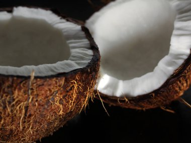 Karanlık bir arka plan üzerine kıyılmış taze Hindistan cevizi iki yarısı