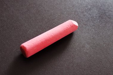 pembe tebeşir parçası bir manyetik tahta kahverengi bir arka plan üzerinde yatıyor ve bir gölge çevirir