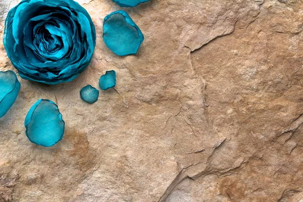 Krásná modrá květina a okvětní lístky z tkaniny na pozadí kamenné textury — Stock fotografie