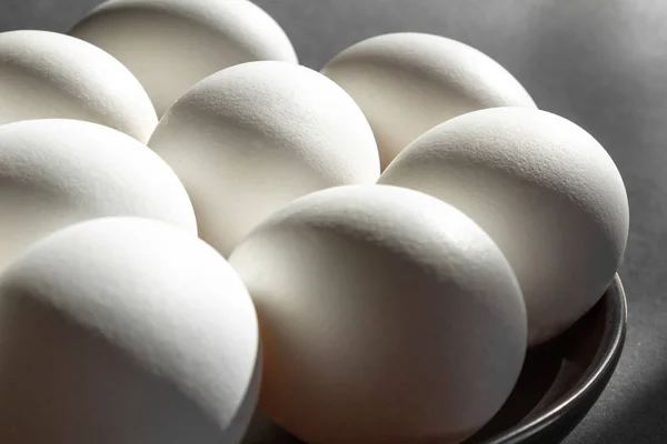 Karanlık arka planda siyah bir kase çiğ tavuk beyaz yumurta — Stok fotoğraf