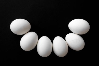 siyah arka plan üzerine yanında altı beyaz tavuk yumurtası