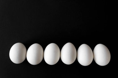 yanında siyah arka plan üzerine beyaz Paskalya yumurtaları