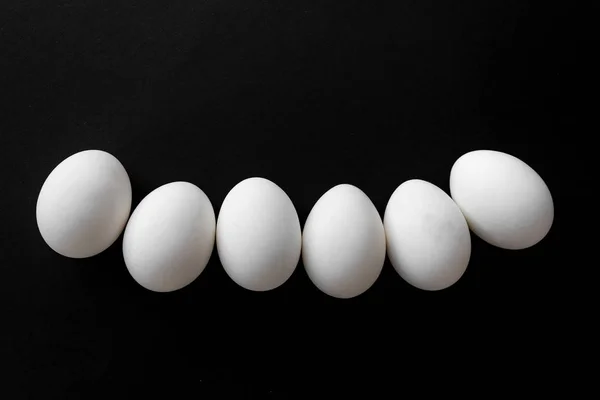 Sei uova di pollo bianco accanto su sfondo nero con posto per iscrizione — Foto Stock