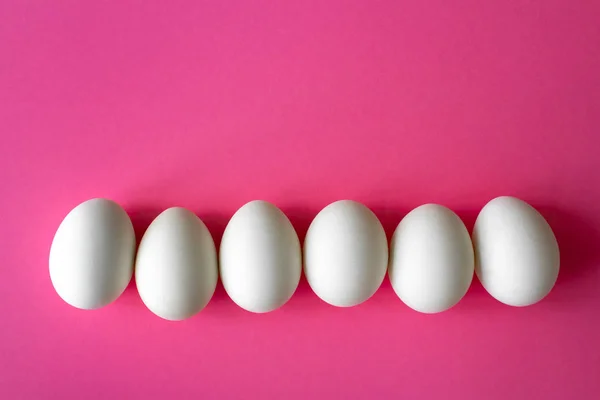 Altı boş beyaz tavuk yumurtası yanında parlak pembe renk arka plan üzerinde — Stok fotoğraf