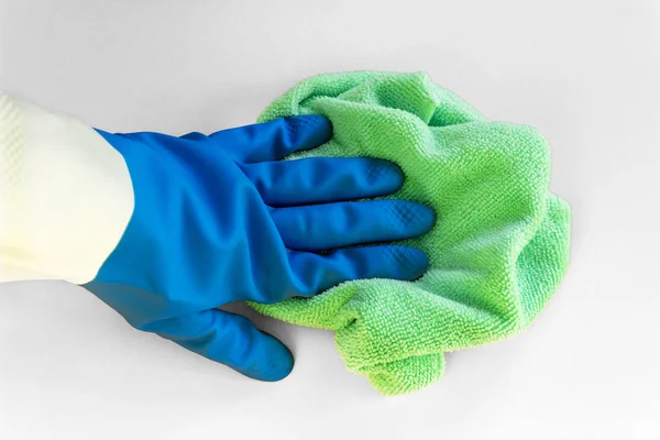 Eine Hand in einem blauen Gummihandschuh hält einen hellen Mikrofaserstaub auf weißem Hintergrund. Konzept des hellen Frühlings, Frühjahrsputz — Stockfoto