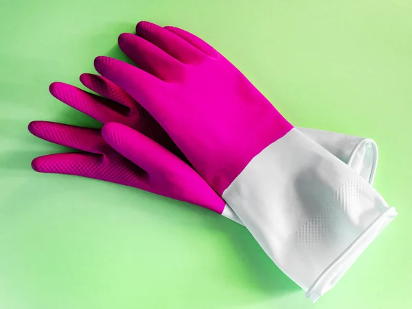 Närbild ovanifrån vackra rosa latex handskar på grön bakgrund. hushållsarbete koncept. Allmänna eller vanlig rensning. Kommersiell städfirma. hushållsapparater och rengöring handskar — Stockfoto