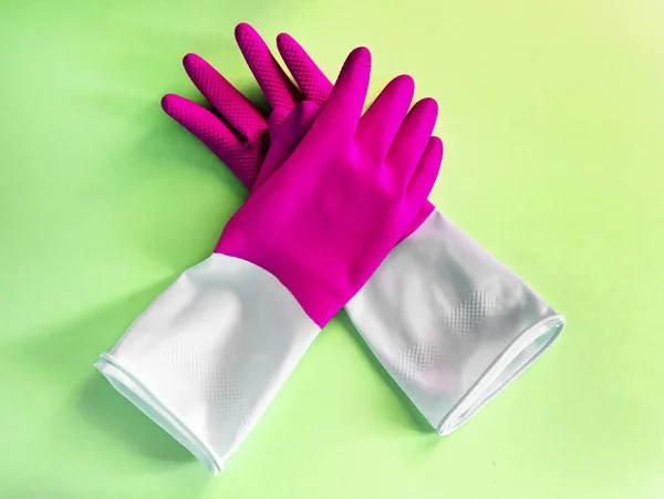 Närbild ovanifrån vackra rosa latex handskar på grön bakgrund. hushållsarbete koncept. Allmänna eller vanlig rensning. Kommersiell städfirma. hushållsapparater och rengöring handskar — Stockfoto