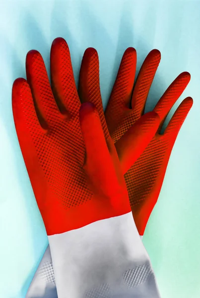 pair Red rubber gloves for cleaning on blue background, with shadow, top view. housework concept. General or regular cleanup. Commercial cleaning company