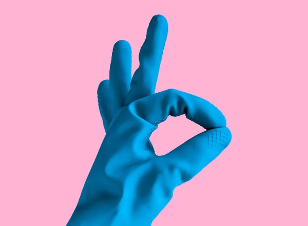 Mão em borracha luva azul mostra sinal ok, objeto isolado no fundo pastel rosa — Fotografia de Stock