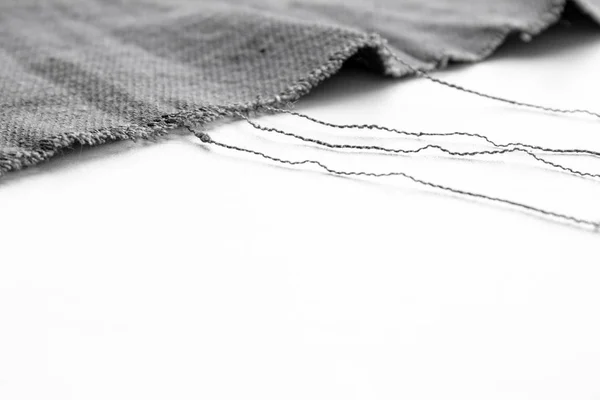 Beyaz arka plan üzerinde iplikleri ile gri kumaş parçası — Stok fotoğraf