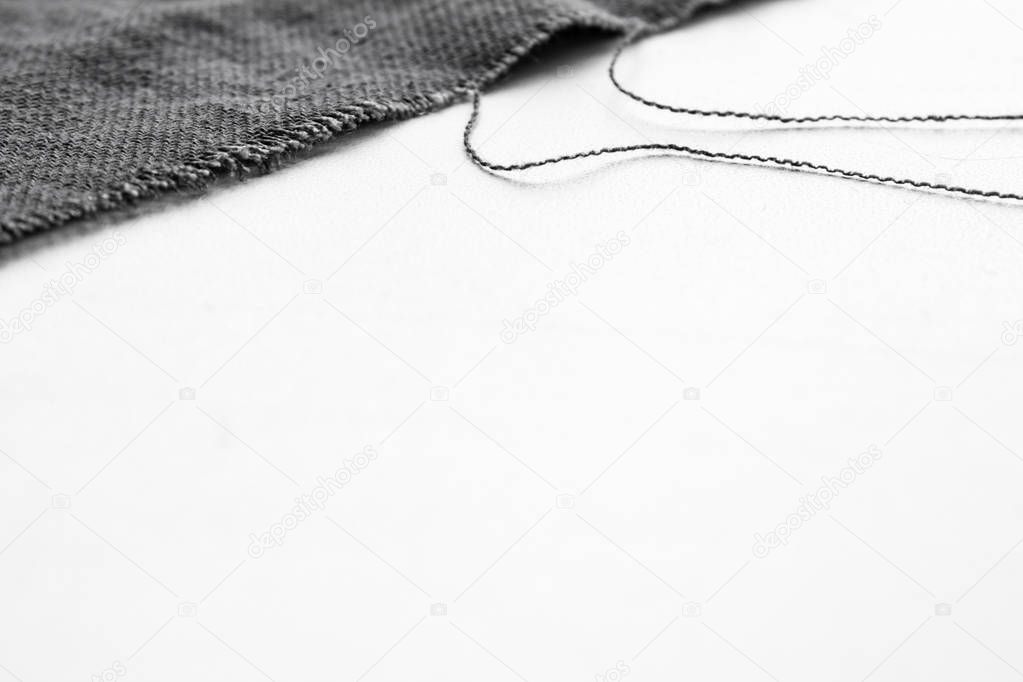 piece of gray fabric with threads on white background