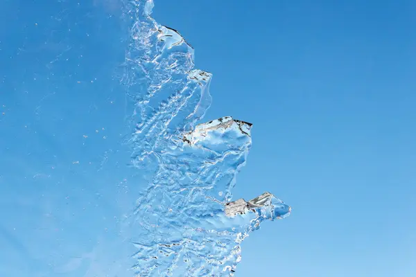 Кусочек тонкого структурного льда напротив голубого неба, концепция таяния льда — стоковое фото