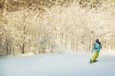 Asha, Rusya - 27 Nisan 2011: parlak bir takım elbise, gözlük ve bir snowboard bir kask olmadan bir kız yamaç aşağı yuvarlanıyor, saçları uçuyor,