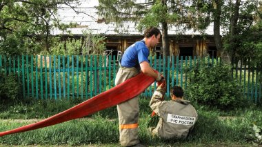 Urman, Rusya - 28 Mayıs 2011: Rusya'nın Urman köyünde ilkbaharda çıkan yangın, patlama ve yangınları söndürdükten sonra iki itfaiyeci kırmızı yangın hortumu çıkardı