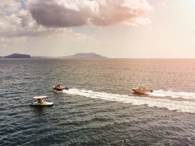 İki tekne ve bir katamaran helikopter havadan görünümü, onlar deniz yüzeyi furrow ve deniz, dağlar, kümülüs bulutlar ve şafak ışınları arka plan karşı deniz köpüğü beyaz şeritler bırakın