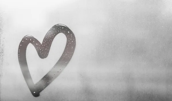 Сіре серце, намальоване на спітнілому склі, є багато крапель на ньому, напис серце і любов, використовуючи ручної роботи на вологому сірому осінньому туманному склі — стокове фото