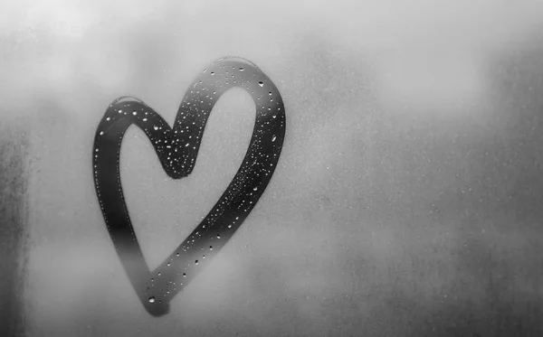 Dark gray heart painted on sweaty glass, there are many drops on it, inscription heart and love using handmade on wet gray autumn foggy glass — Stock Photo, Image