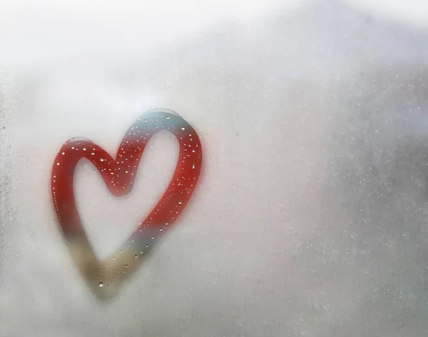 Κόκκινο περίγραμμα καρδιά ζωγραφισμένο σε ιδρωμένη γυαλί, υπάρχουν πολλές σταγόνες σε αυτό, επιγραφή καρδιά και την αγάπη χειροποίητα σε βρεγμένο φθινόπωρο γυαλί ομίχλη — Φωτογραφία Αρχείου