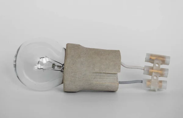 incandescent lamp bulb with cap, socket, wires and terminal block lies on white background, new idea concept