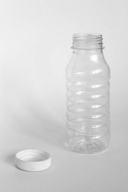 kapak olmadan boş şeffaf açık plastik şişe, kapak beyaz bir arka plan yanında yatıyor, enkaz kaldırma kavramı