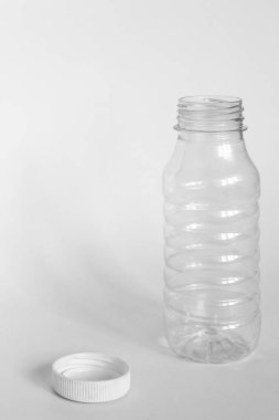 kapak olmadan boş şeffaf açık plastik şişe, kapak beyaz bir arka plan yanında yatıyor, enkaz kaldırma kavramı