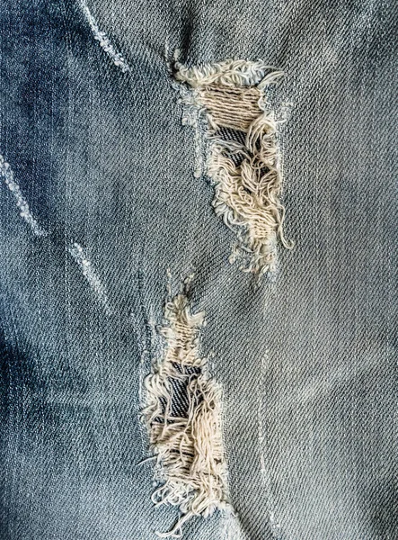 Divatos lyuk a farmer Jeans. Hasogatott megsemmisült Torn Blue farmer háttér. Közelről kék farmer textúra — Stock Fotó