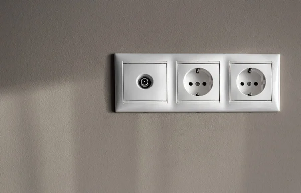 Enchufes eléctricos, un conjunto de tres enchufes eléctricos blancos vacíos para electrodomésticos y un conector de antena para un televisor en gris vacío — Foto de Stock