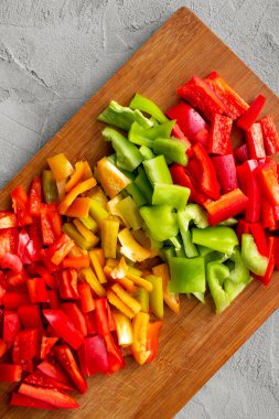 Renkli doğranmış dolmalık biberler - kırmızı, sarı, yeşil - tahta üzerinde büyük küplerle kesilmiş