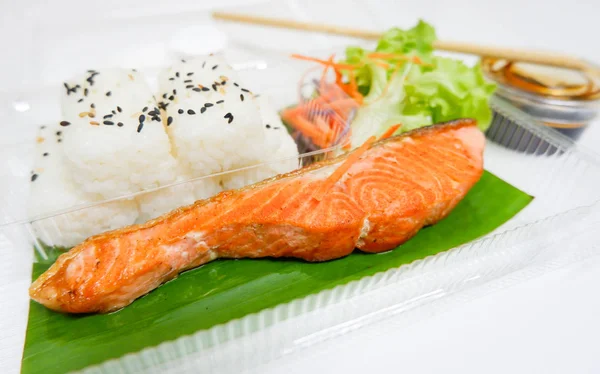Lunch  box  with grilled salmon fish, rice, salad and sauce