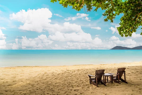 Ξύλινες καρέκλες στην αμμώδη παραλία με δέντρο, βουνό και όμορφη θέα στη θάλασσα — Φωτογραφία Αρχείου