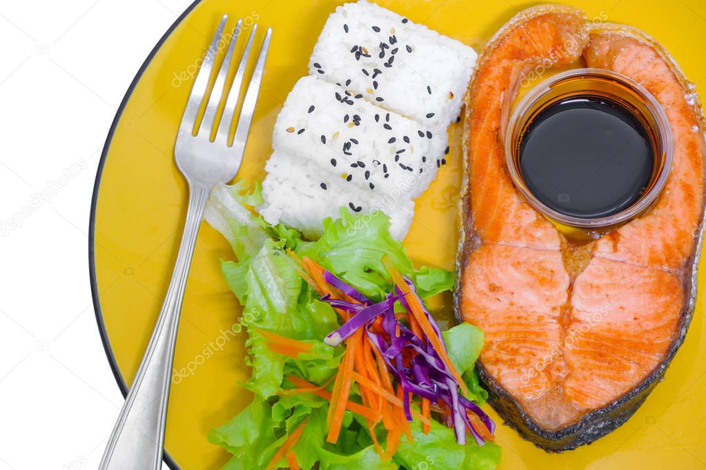 Grilled salmon fish,rice,sesame seeds, salad,fork and Teriyaki sauce in yellow dish on white background