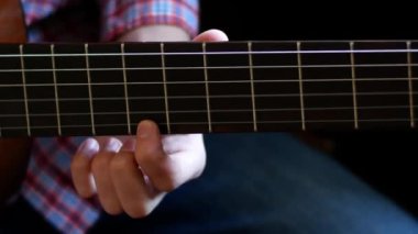 Çocuk klasik gitar çalmayı öğren. Yakından kapatın. Parmaklar tellere dokunuyor