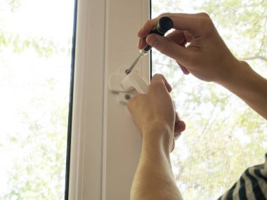 bir adam bir pencereyi tamir eder, bir kolu yakından sabitler