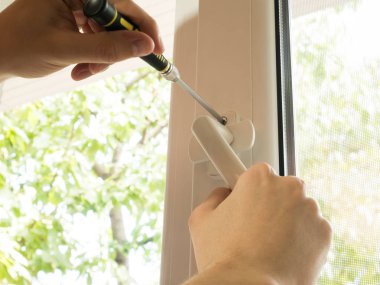 bir adam bir pencereyi tamir eder, bir kolu yakından sabitler