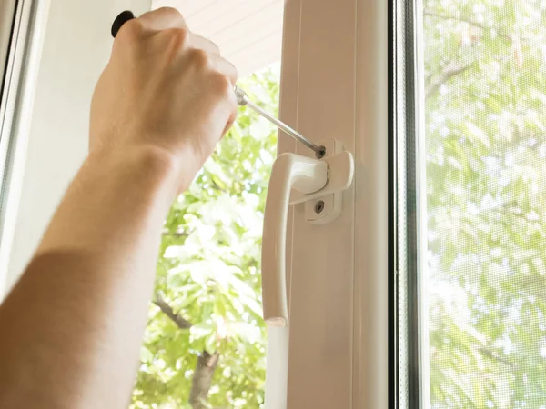 a man fixes a window, fastens a handle close up