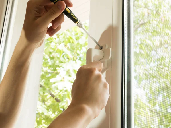 bir adam bir pencereyi tamir eder, bir kolu yakından sabitler