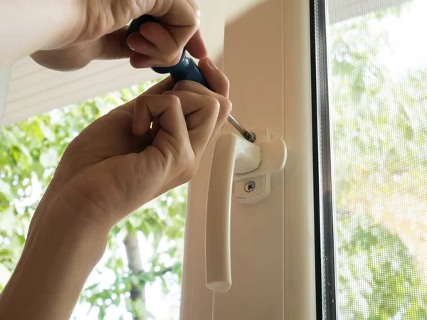 bir adam bir pencereyi tamir eder, bir kolu yakından sabitler