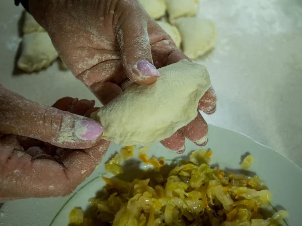 woman sculpts dumplings with stewed cabbage